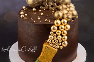 35-års tårta med champagneflaska och bubblor samt siffror av choklad (de mindre är strössel).