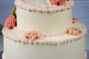 Bröllopstårta i två lager dekorerad med spritsade blommor.