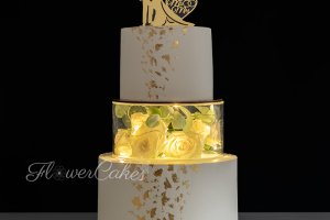 Bröllopstårta med mellanlager av akryl med blommor och ljusslinga för fin effekt i mörkret.